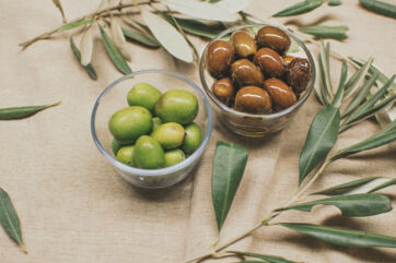 Green and black olives in bowls with olive branches. Extra virgin olive oil ingredient-Italian olive oil