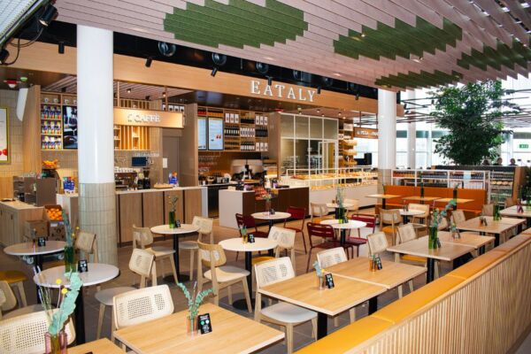 Eataly Amsterdam Schiphol Airport store interior. Tables, chairs, cafe, and bakery. Italian food market.