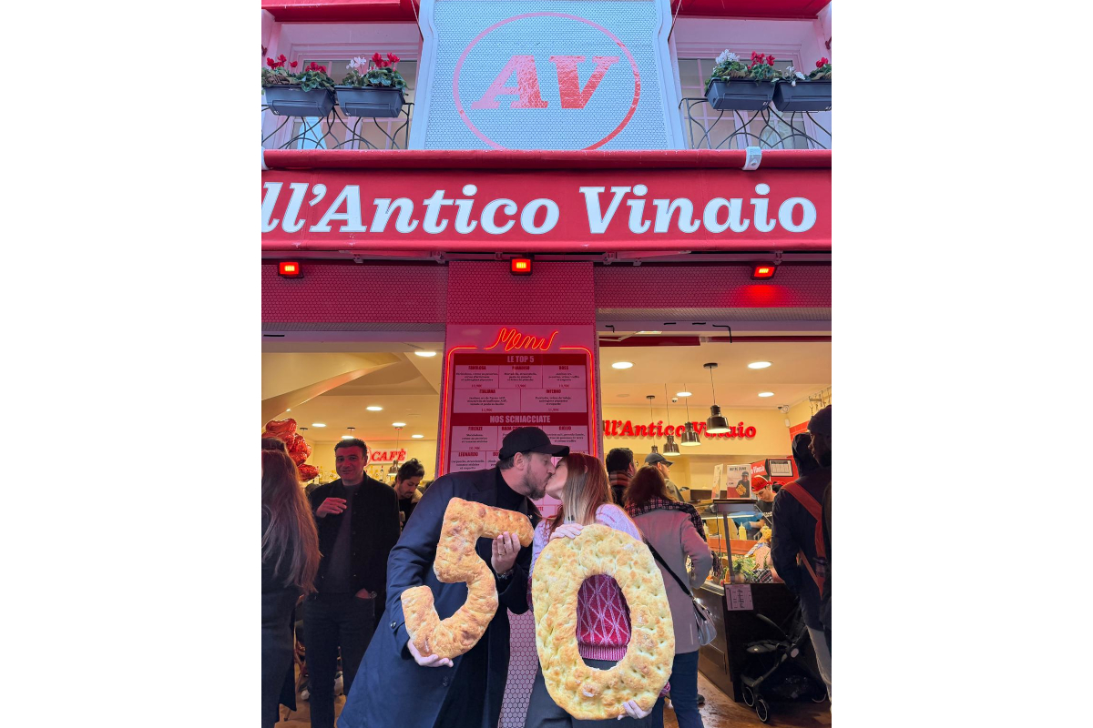All'Antico Vinaio Paris celebrates 50 years! Couple kisses holding bread shaped as 50. Italian sandwich shop anniversary.