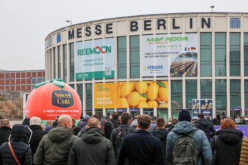 Fruit Logistica trade show in Berlin. Crowd entering Messe Berlin. Banners for fruit sorting solutions and fresh produce.