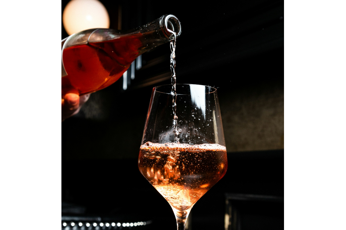 Italian wine-Pouring rosé wine into a glass. Refreshing alcoholic drink. Wine bottle.
