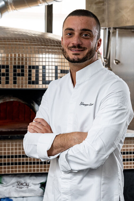 Giuseppe Cutraro, Paris pizza chef. Man in chef's whites with arms crossed, standing in front of a pizza oven.