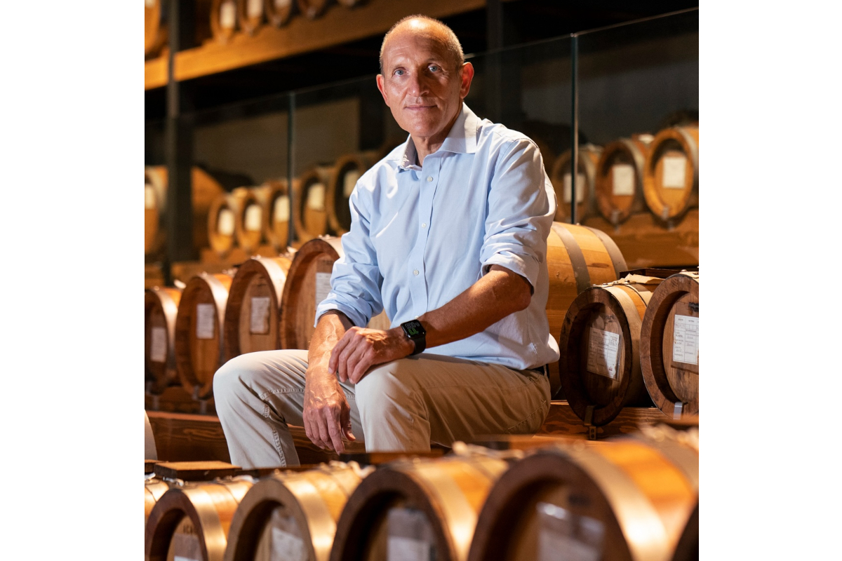 Cesare Mezzetti, President of the Consortium for the Protection of Aceto Balsamico di Modena PGI, seated among balsamic vinegar barrels.