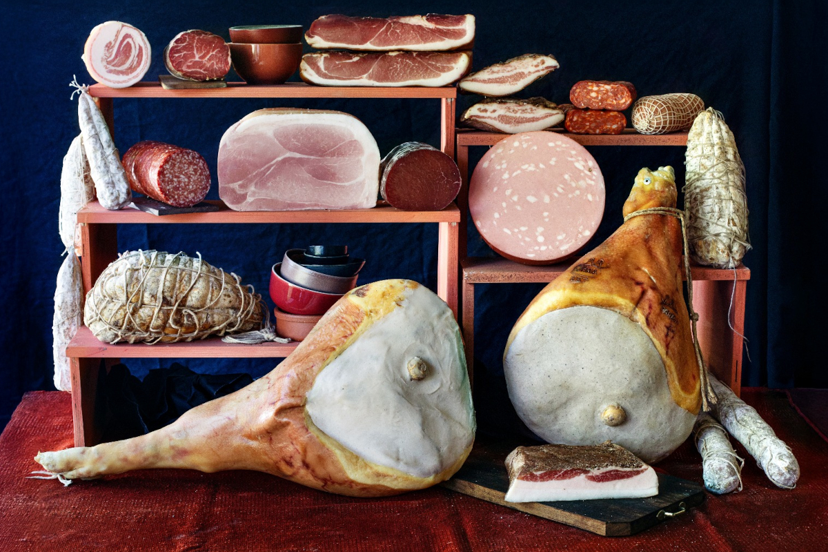 Italian charcuterie display. Assorted cured meats, salami, prosciutto, and mortadella on wooden shelves. Food photography.
