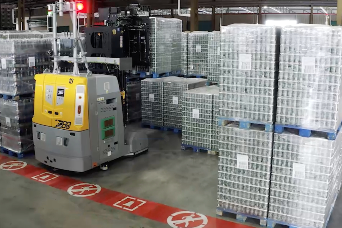 Estrella de Levante & E80 Group: a vision focused on innovation and constant growth Automated guided vehicle (AGV) in a warehouse with stacked pallets of canned goods. Industrial automation.