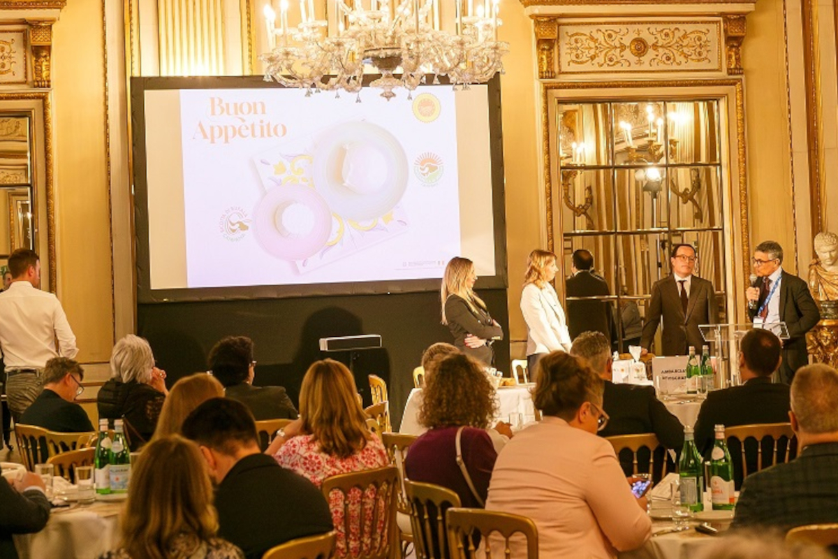 Vienna event with speakers, audience, and Buon Appetito food presentation on screen. - Mozzarella di Bufala Campana PDO