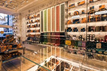 Venchi store at London Gatwick Airport. Chocolate display with colorful candies and gift boxes on shelves.