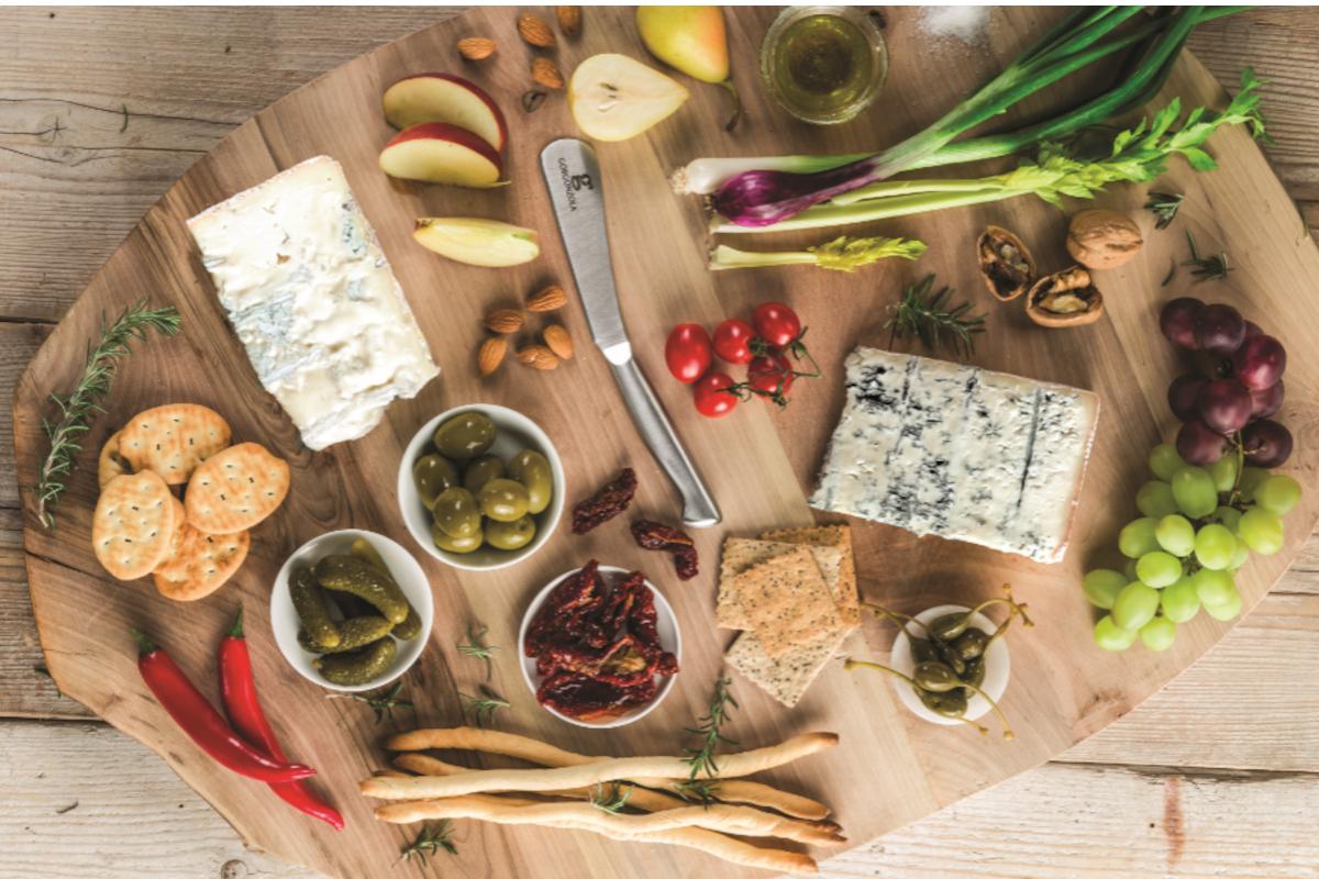 Tagliere di formaggio Gorgonzola con cracker, frutta, noci, olive, peperoni, pomodori e grissini. Piatto di antipasti.