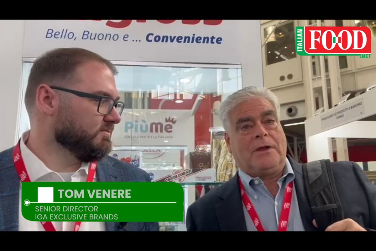 Two men at Italian food expo. Tom Venere, IGA Senior Director, discusses food brands. Trade show.