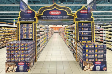 Grocery aisle featuring Barilla pasta Ramadan display. Shelves stocked with food products. Ramadan recipes promotion.