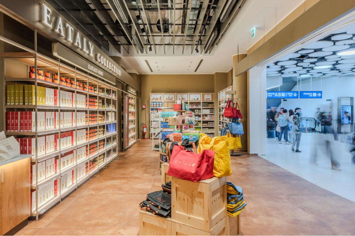 Avolta, Eataly store interior. Shelves stocked with Italian food products and branded tote bags. Eataly Collection.