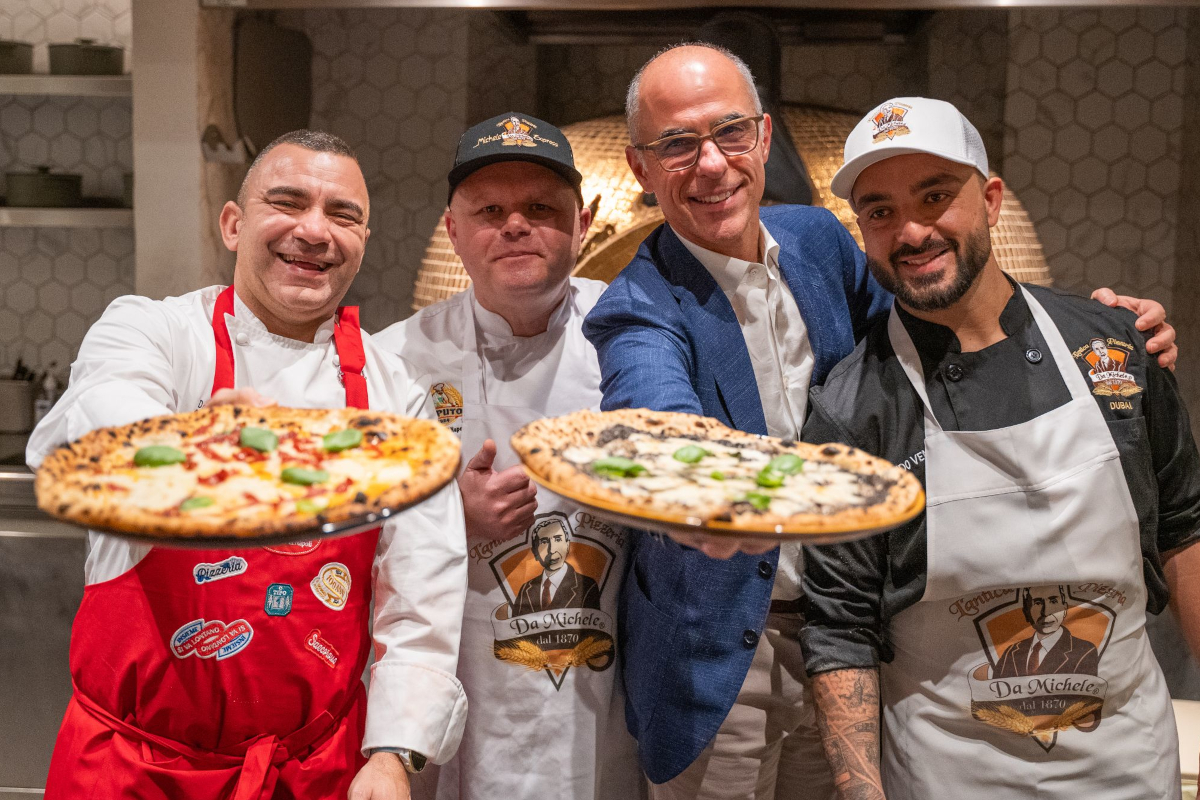 Chefs holding pizza at Da Michele restaurant. Fresh Italian pizza with basil. Eat better, Casinetto. - Italian culinary heritage