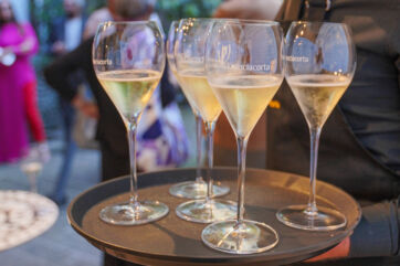 Glasses of Franciacorta sparkling wine on a tray. Celebrate Franciacorta exports growth.