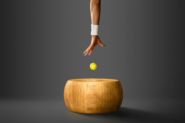Tennis ball above Parmigiano Reggiano cheese wheel, hand with wristband. Conceptual food and sport image. - Miami Open, tennis