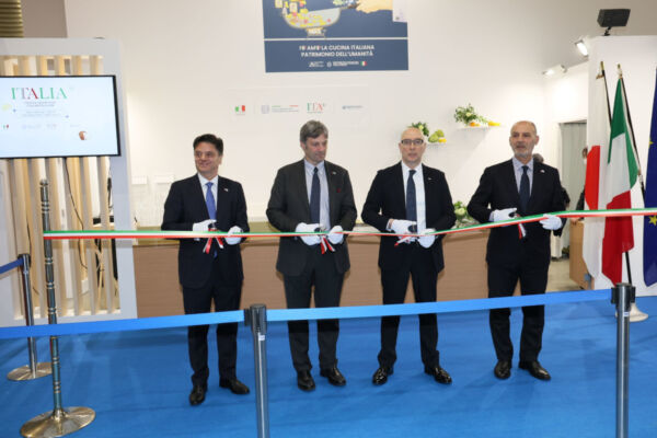 Italian Foodex Japan 2026 ribbon-cutting ceremony. Men in suits cut the ribbon. Italian flags. Food industry event.