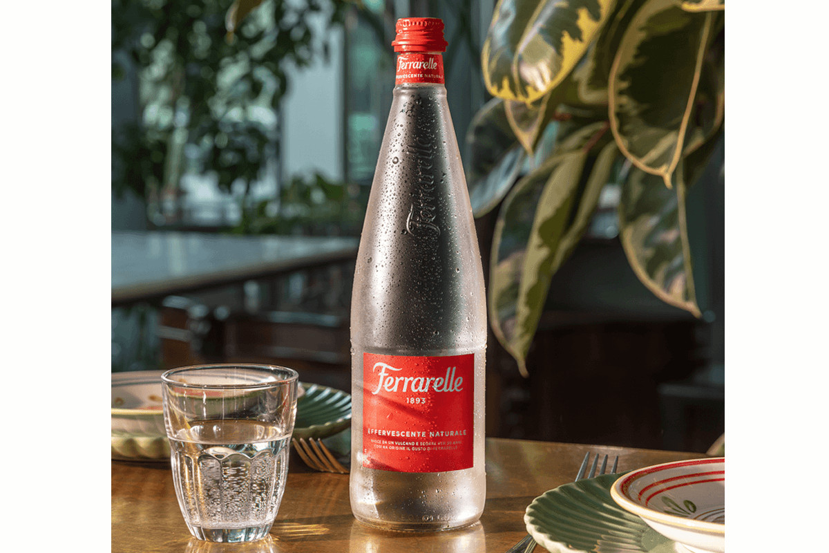 Ferrarelle mineral water bottle with glass. Italian sparkling water brand for U.S. retail expansion.