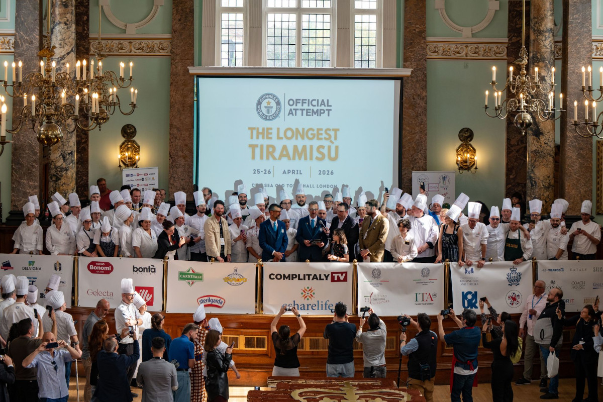 Crowd celebrates Longest Tiramisu Guinness World Record attempt. Chefs in hats, sponsors, and photographers. Tiramisu dessert event.