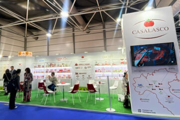 Casalasco Tuttofood trade show booth. Italian food company display with tomato products, map, and seating area.