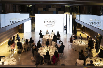 Indoor event for Jimmy Tartufi with guests seated at round tables, speaker on stage.