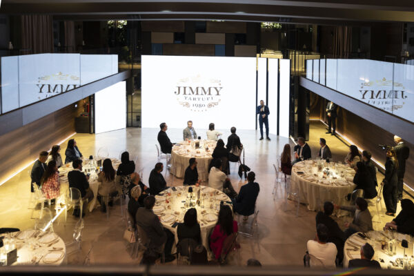 Indoor event for Jimmy Tartufi with guests seated at round tables, speaker on stage.