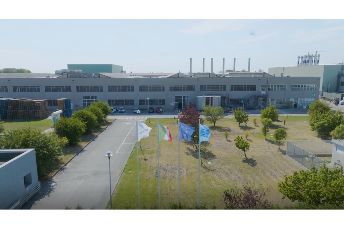 Exterior of Stabilimento di Pomposa, a large industrial building with flags. Manufacturing plant. - E80-Conserve Italia
