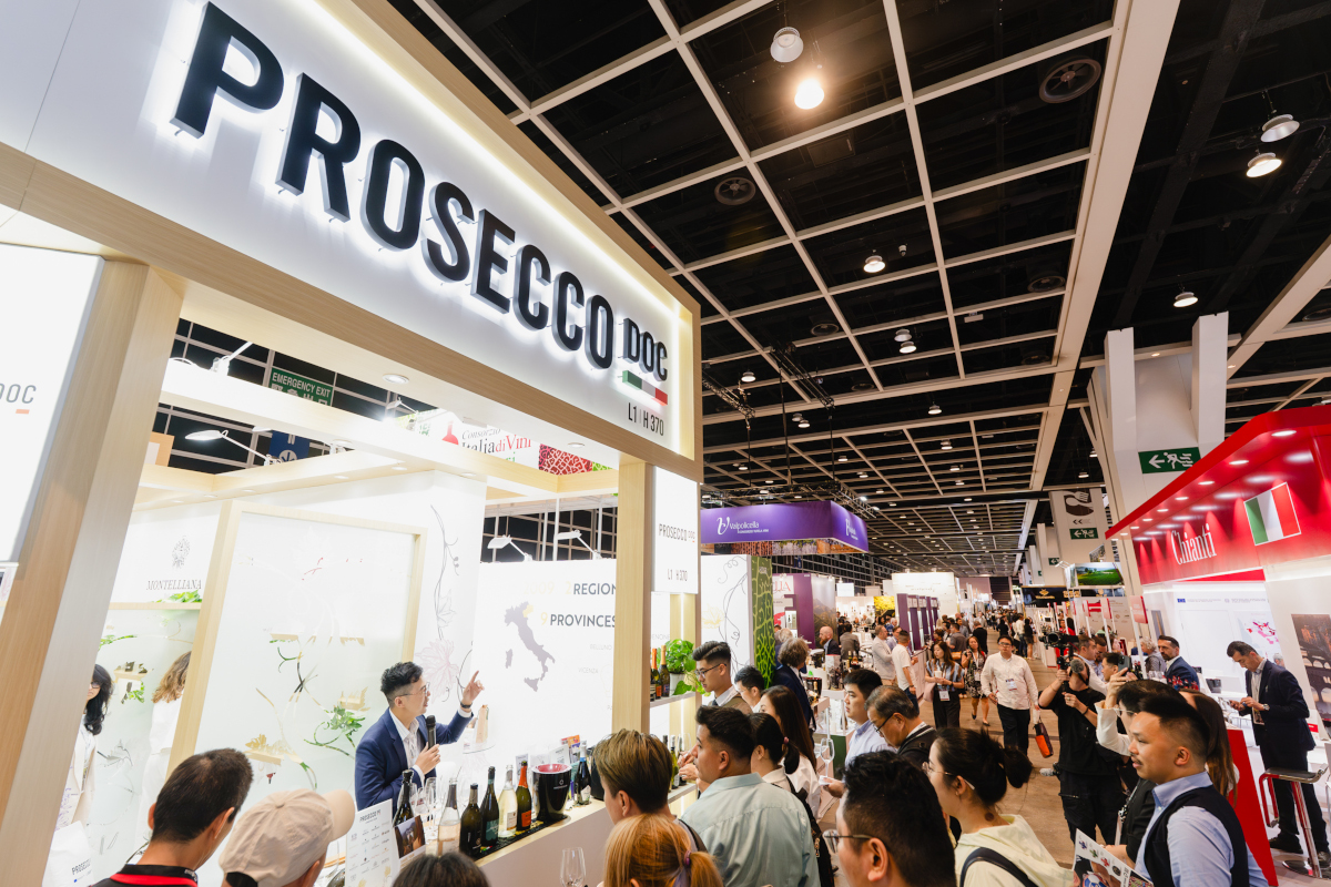 Crowd at Vinexpo Hong Kong wine trade show. Prosecco DOC booth with presenter.