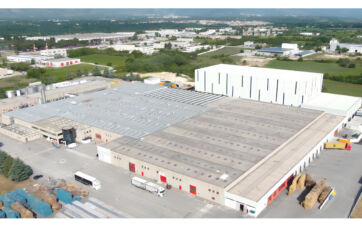 Aerial view of the Refresco Italia manufacturing plant in Sulmona, featuring industrial buildings and freight trucks.