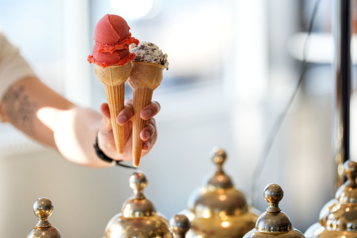 Hand holding two waffle cones with scoops of red strawberry sorbet and cookies and cream gelato at an Eataly ice cream bar-Empire State Building-Eataly