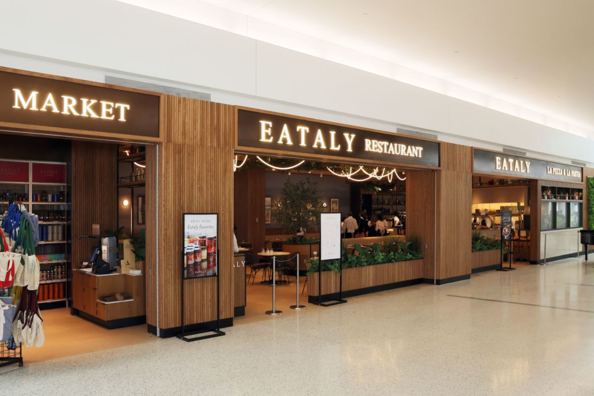 Eataly restaurant and market storefront with wooden accents, modern lighting, and signage in an airport terminal setting.