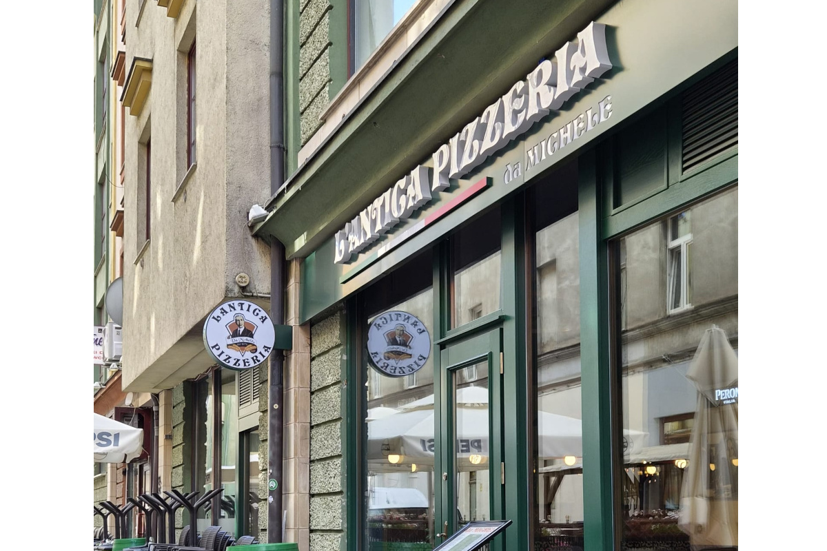 Exterior of L'Antica Pizzeria da Michele in Wroclaw with green storefront signage and a round restaurant logo sign.