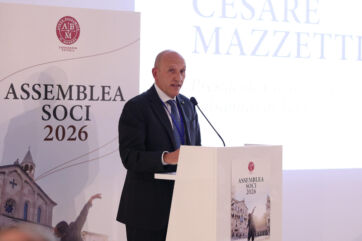 Cesare Mazzetti speaking at the Aceto Balsamico di Modena PGI assembly, standing at a podium with event branding.