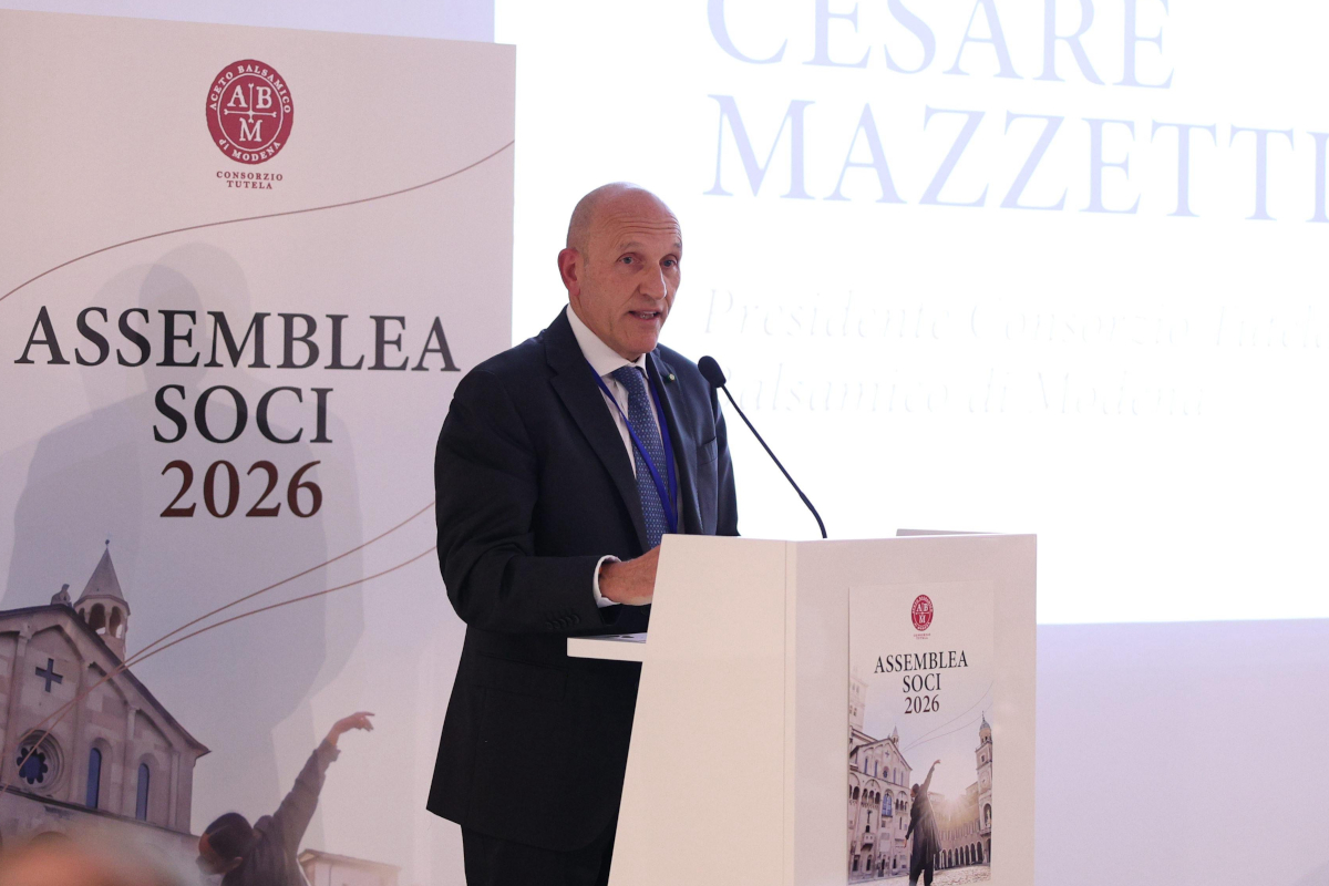 Cesare Mazzetti speaking at the Aceto Balsamico di Modena PGI assembly, standing at a podium with event branding.