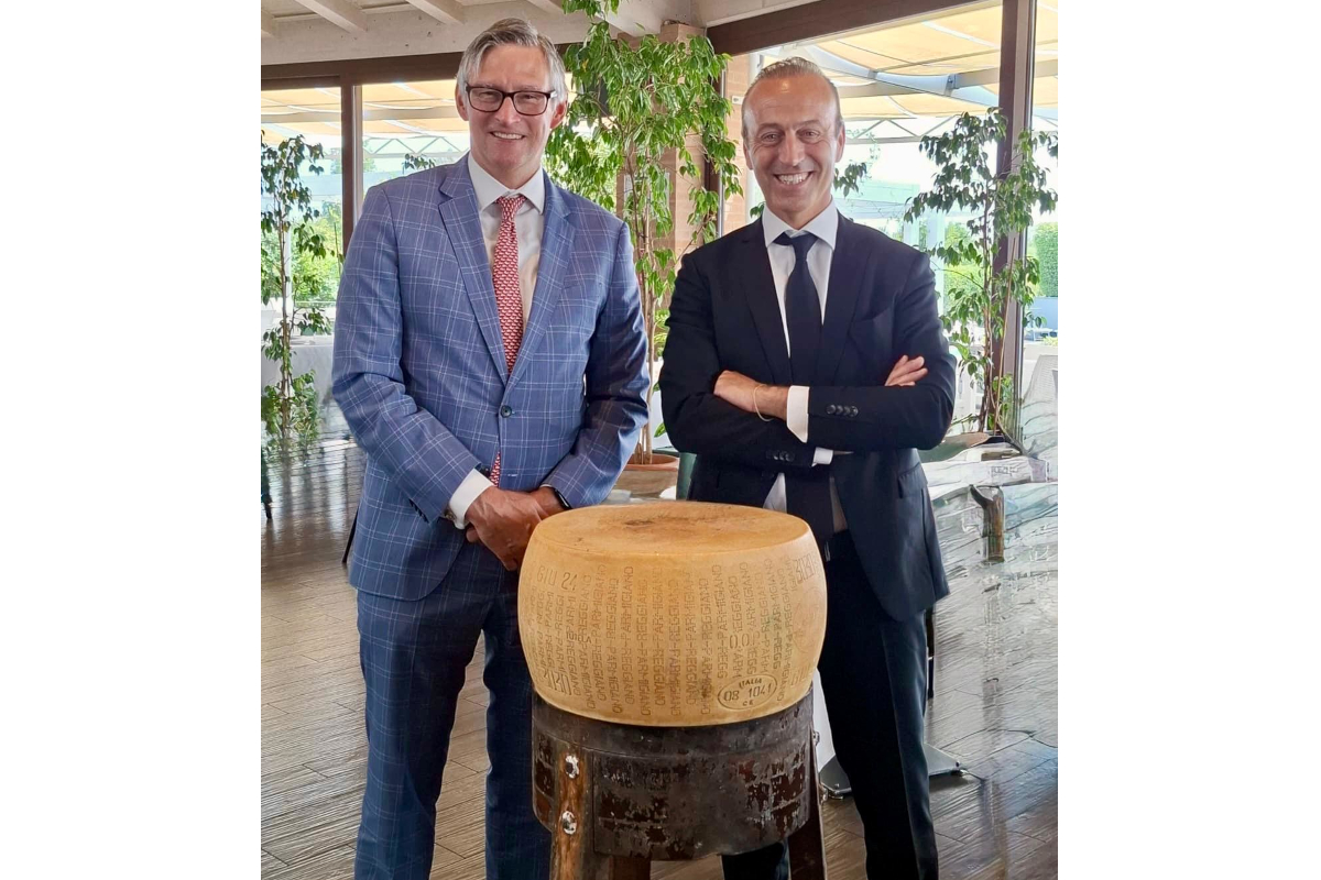 US Consul General Douglass Benning visits the Parmigiano Reggiano supply chain, standing with a wheel of Italian cheese.