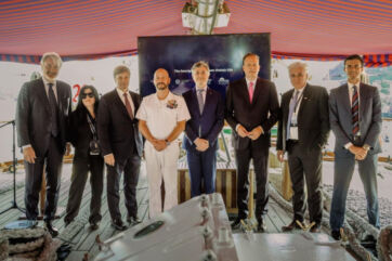 Group of officials and a naval officer posing for a photo at the Vinitaly USA event aboard the Amerigo Vespucci ship.