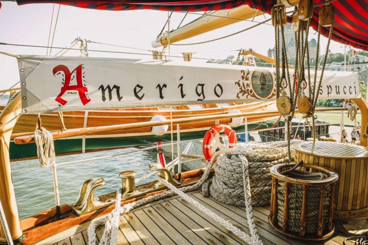 Wooden deck of the Italian tall ship Amerigo Vespucci featuring nautical ropes, brass fittings, and a branded banner.