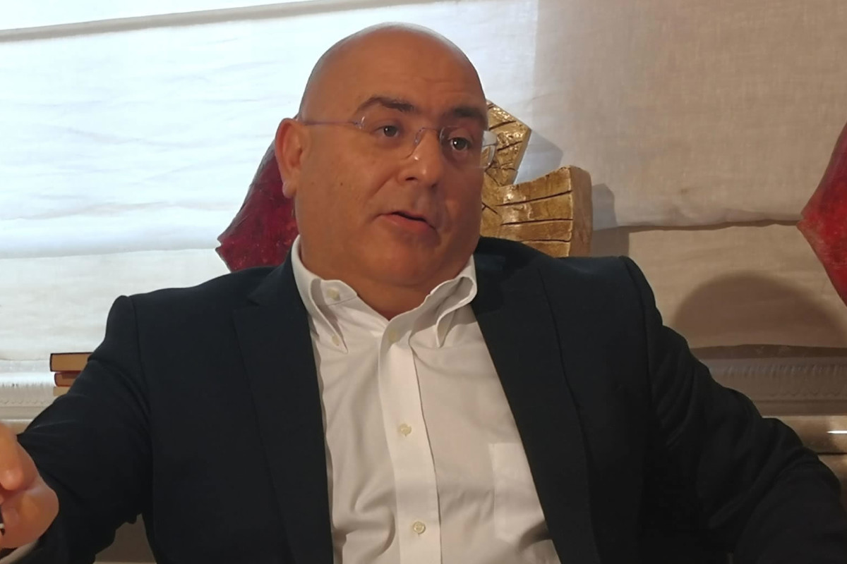 Gianni Maoddi, President of the Pecorino Romano PDO Consortium, in a suit and white shirt, speaking during an interview.