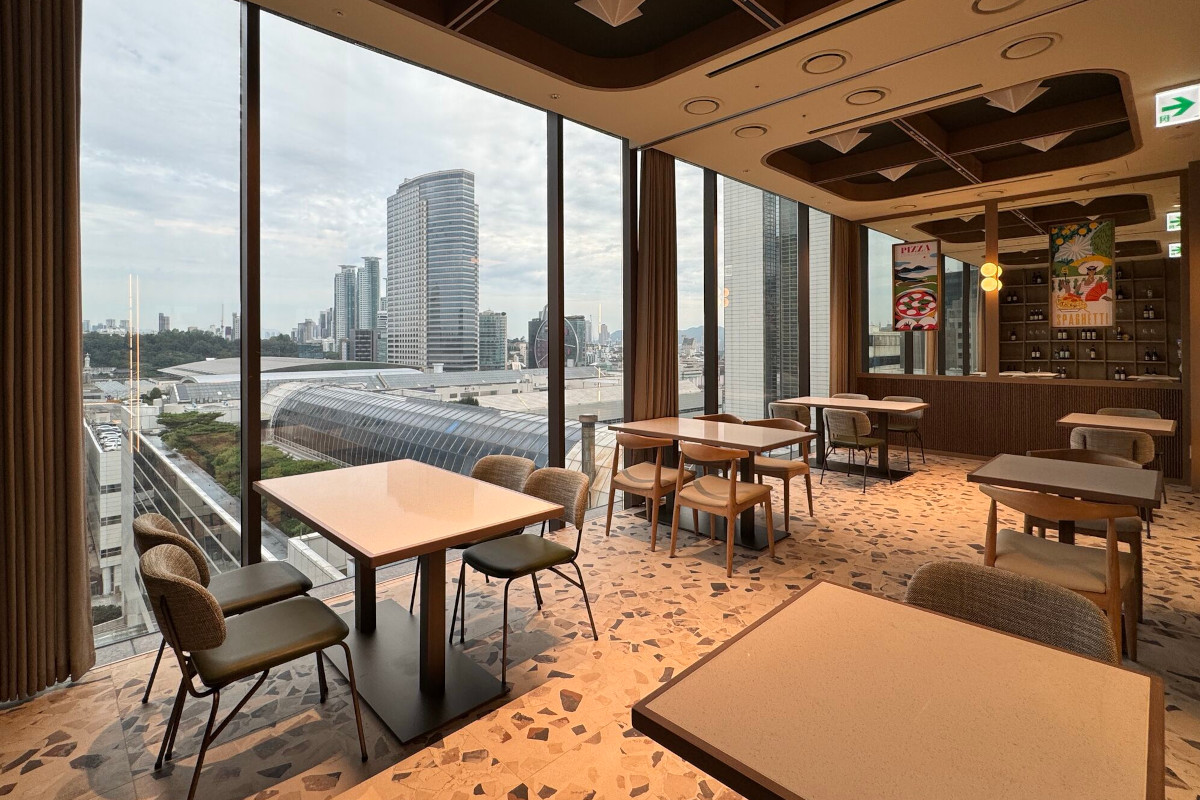 Modern dining area at Eataly Seoul in Gangnam with floor-to-ceiling windows overlooking the city skyline and skyscrapers.