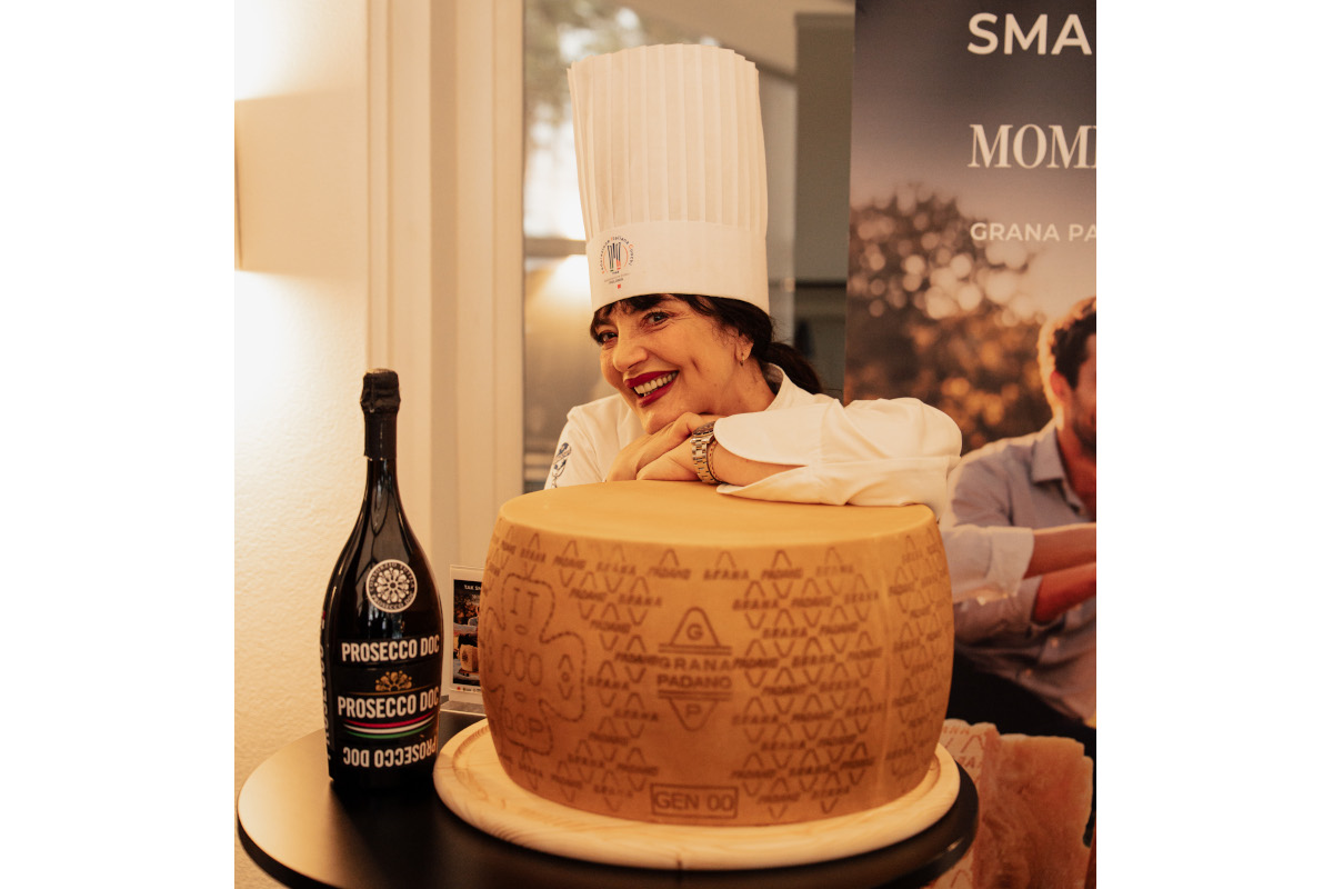 Chef Cristina Catese posing with Prosecco DOC bottle and Grana Padano PDO cheese wheel at Warsaw influencer dinner event.