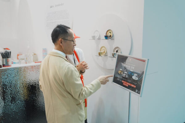 Man pointing at an illy Art Collection display by John Armleder featuring designer espresso cups at Frieze Seoul.