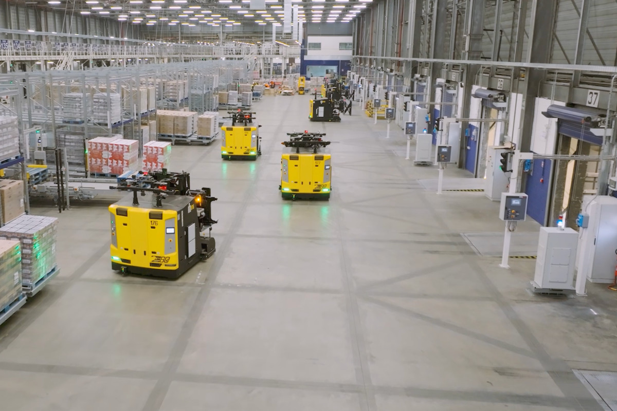 Automated yellow LGVs operating in a warehouse truck loading area for last-mile intralogistics.
