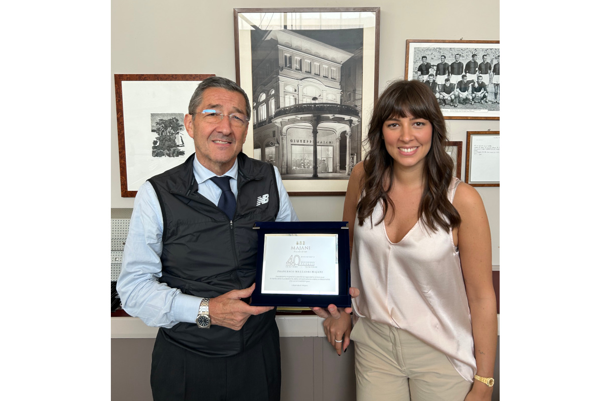 Francesco Majani Mezzadri and Vittoria Majani Mezzadri holding framed certificate, standing in office with historic building photos.