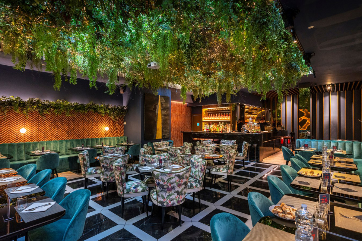 Soffitto verde artificiale di design per ristorante. Arredo con piante finte e illuminazione.