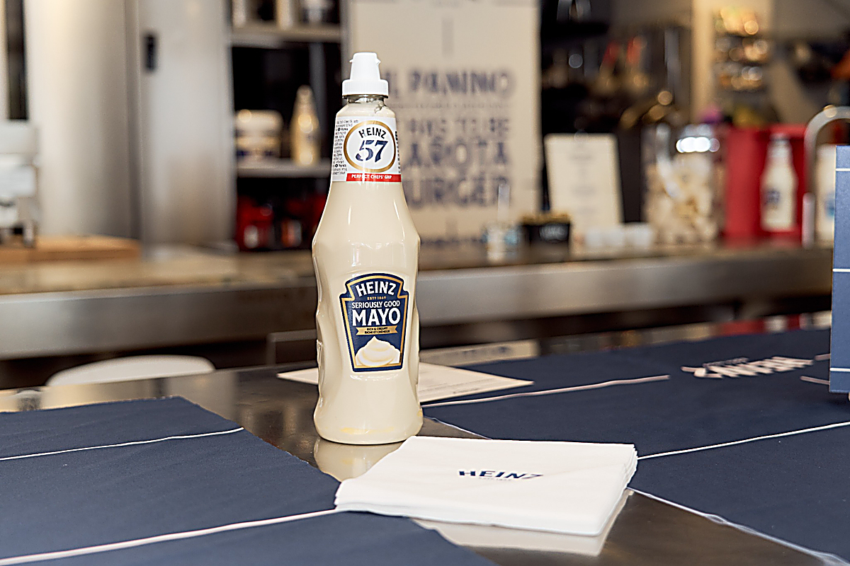 Flacone di Heinz Seriously Good Mayo su bancone professionale con tovagliolo brandizzato per la ristorazione.