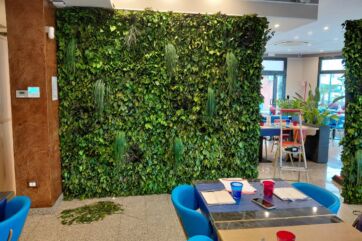 Parete di verde stabilizzato su misura per il design di un ristorante, con piante rigogliose e arredi moderni.