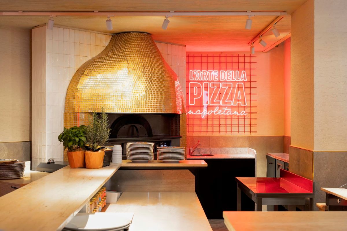 Interno del ristorante Rossopomodoro: forno per pizza napoletana, insegna al neon L'arte della pizza.