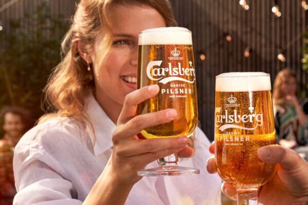 Carlsberg: donna con bicchiere di birra Pilsner. Crescita solida Carlsberg Group.