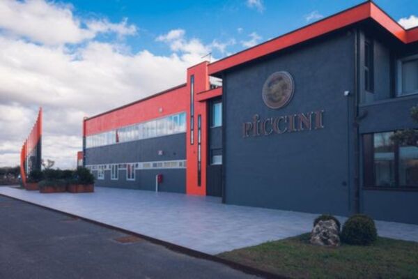 Esterno cantina Piccini 1882. Architettura moderna, colori rosso e grigio. Vino toscano, innovazione e crescita.