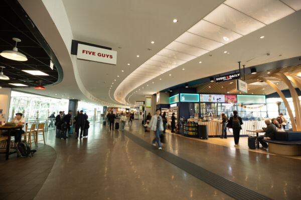 Food court top 30: area ristorazione con Five Guys e Sushi Daily, persone in transito.