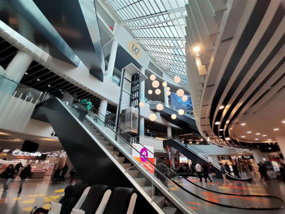 Food court con scale mobili. Interni moderni, illuminazione sferica. Ristorazione e negozi.