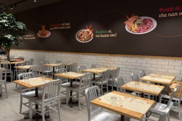 Interni Dispensa Emilia Liguria: tavoli, sedie, decorazioni murali con piatti tipici emiliani. Ristorante accogliente.